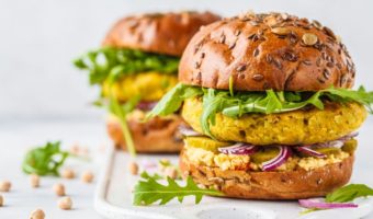 plant-based chickpea burgers with hummus, pickles cucumbers, and arugula
