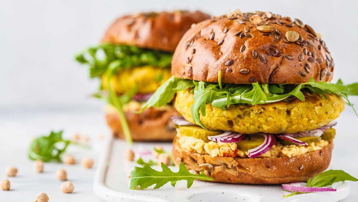 plant-based chickpea burgers with hummus, pickles cucumbers, and arugula