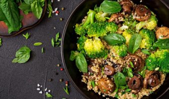 plant-based vegan salad with quinoa, spinach, broccoli, and mushrooms in a bowl
