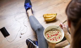 plant-based diet for athletes.young fit girl eating oatmeal with berries in workout clothes