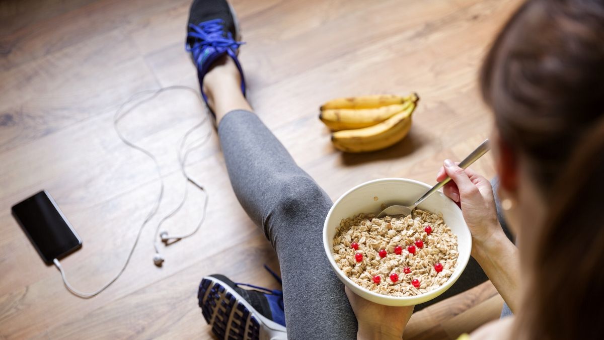 plant-based diet for athletes.young fit girl eating oatmeal with berries in workout clothes